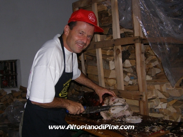Un volontario mentre taglia la porchetta
