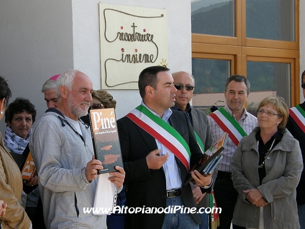 Il Sindaco di Baselga di Piné Ugo Grisenti consegna dei libri al presidente di Ricostruire Insieme